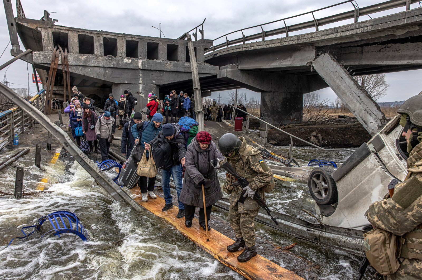 People cross a destroyed bridge as they flee from the front line town of Irpin, Kyiv region, Ukraine, March 7, 2022.  (EPA Photo)