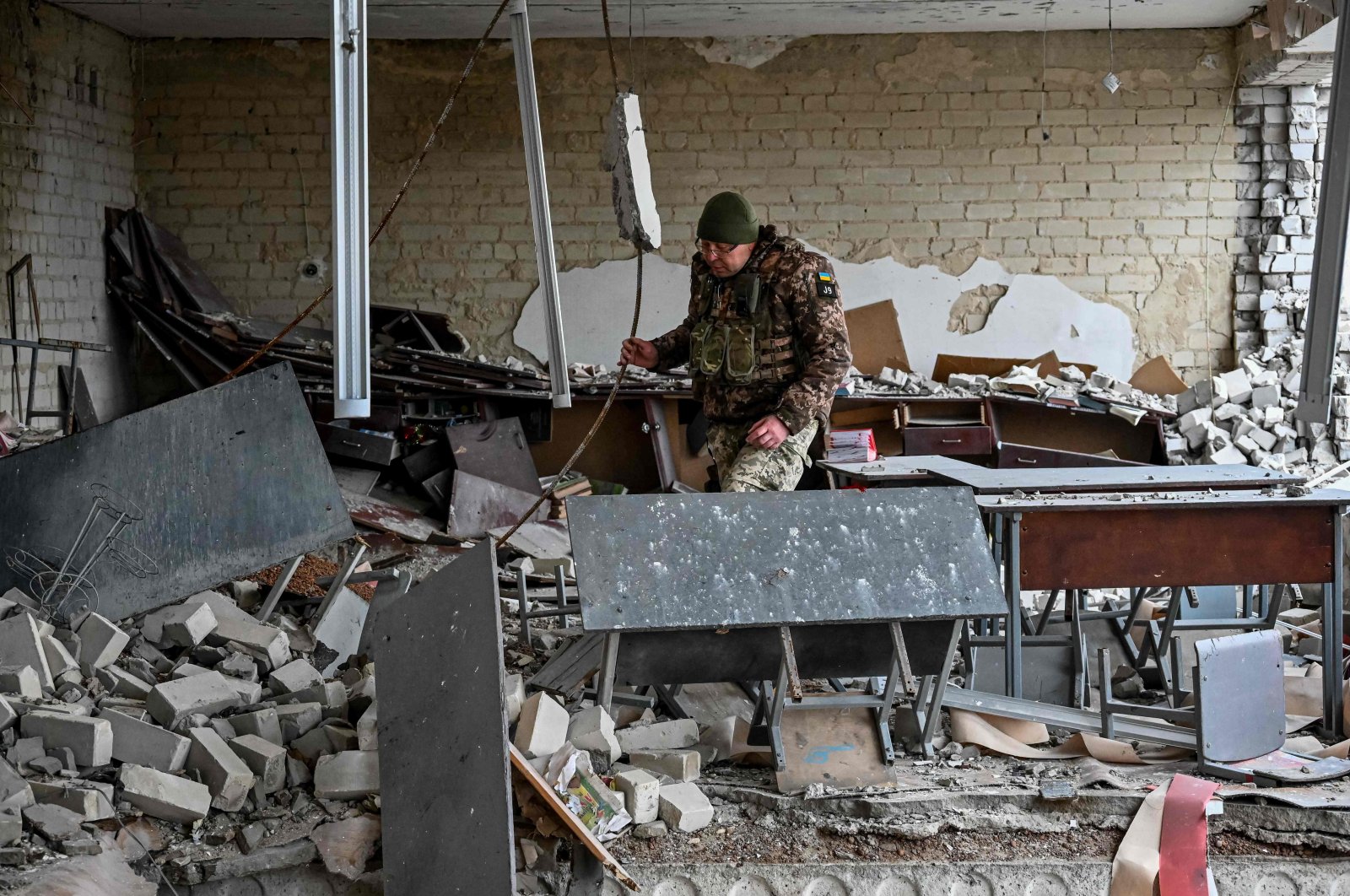 A Ukrainian serviceman inspected a room in the damaged school building in the liberated village of Petropavlivka near Kupiansk, Kharkiv region on Dec.15, 2022, amid the Russian invasion of Ukraine. (AFP Photo)