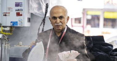 Doğan steams and irons paper notes as a hygiene measure, Dec. 19, 2022. (AA photo)