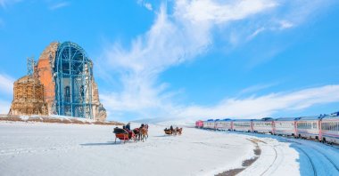 The Eastern Express train rides past the Ani ruins as horses pull a couple of sleighs on the snow, in Kars, Türkiye. (Shutterstock Photo)