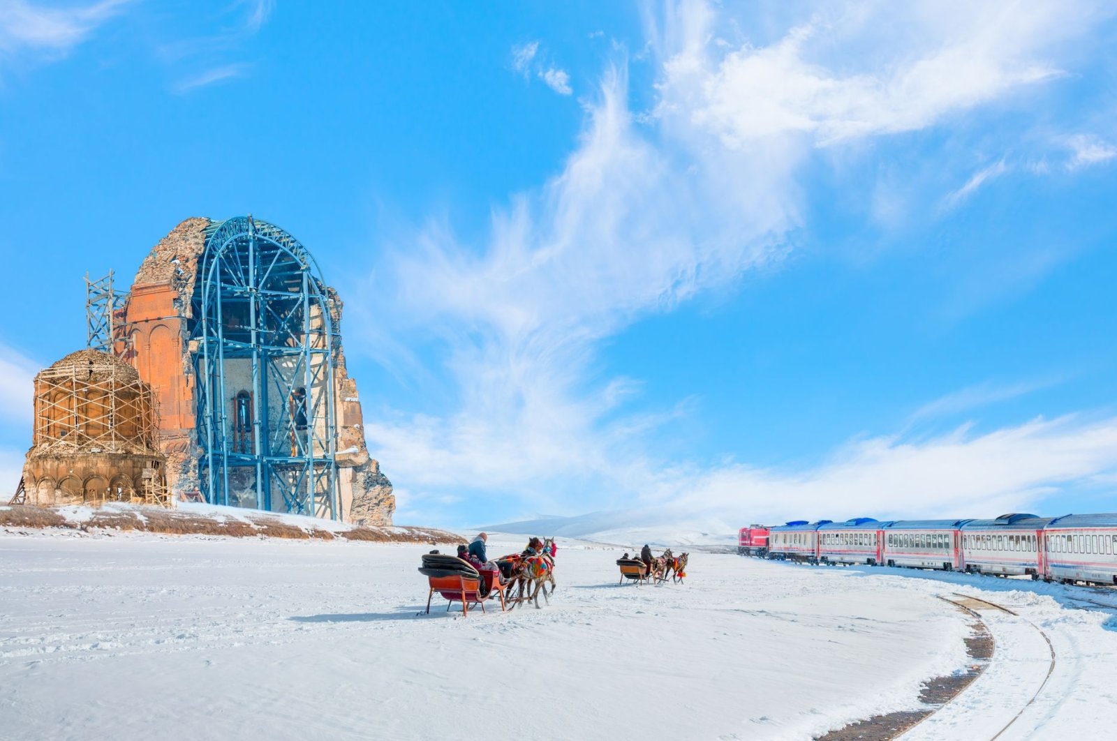 The Eastern Express train rides past the Ani ruins as horses pull a couple of sleighs on the snow, in Kars, Türkiye. (Shutterstock Photo)