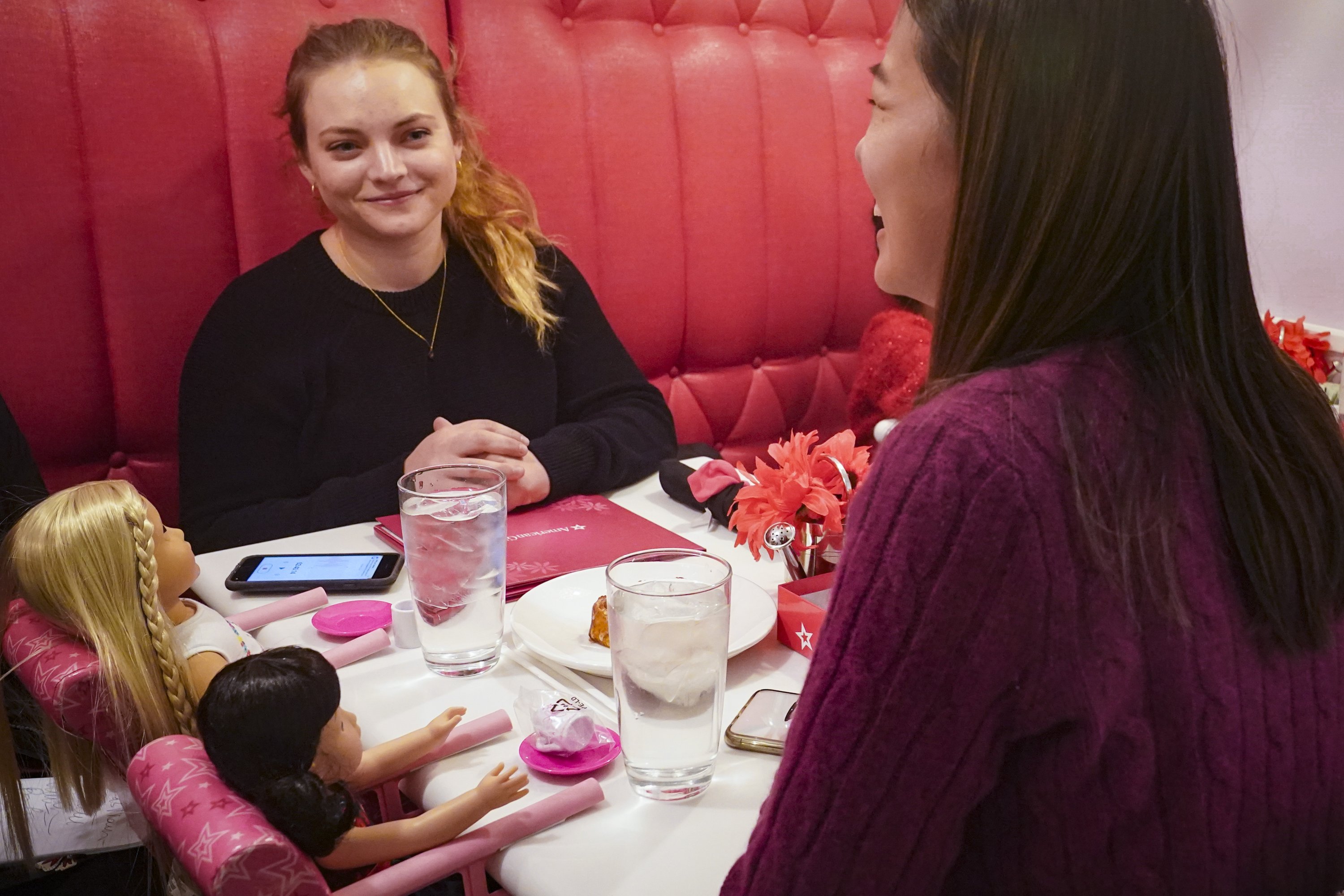 Marisa Dragos (kiri), 23, bersama teman masa kecilnya Lisa Costantino (kanan), 24, duduk untuk makan siang di American Girl Cafe dengan dua boneka pinjaman toko, di New York, AS, 2 Desember 2022. (AP Foto)