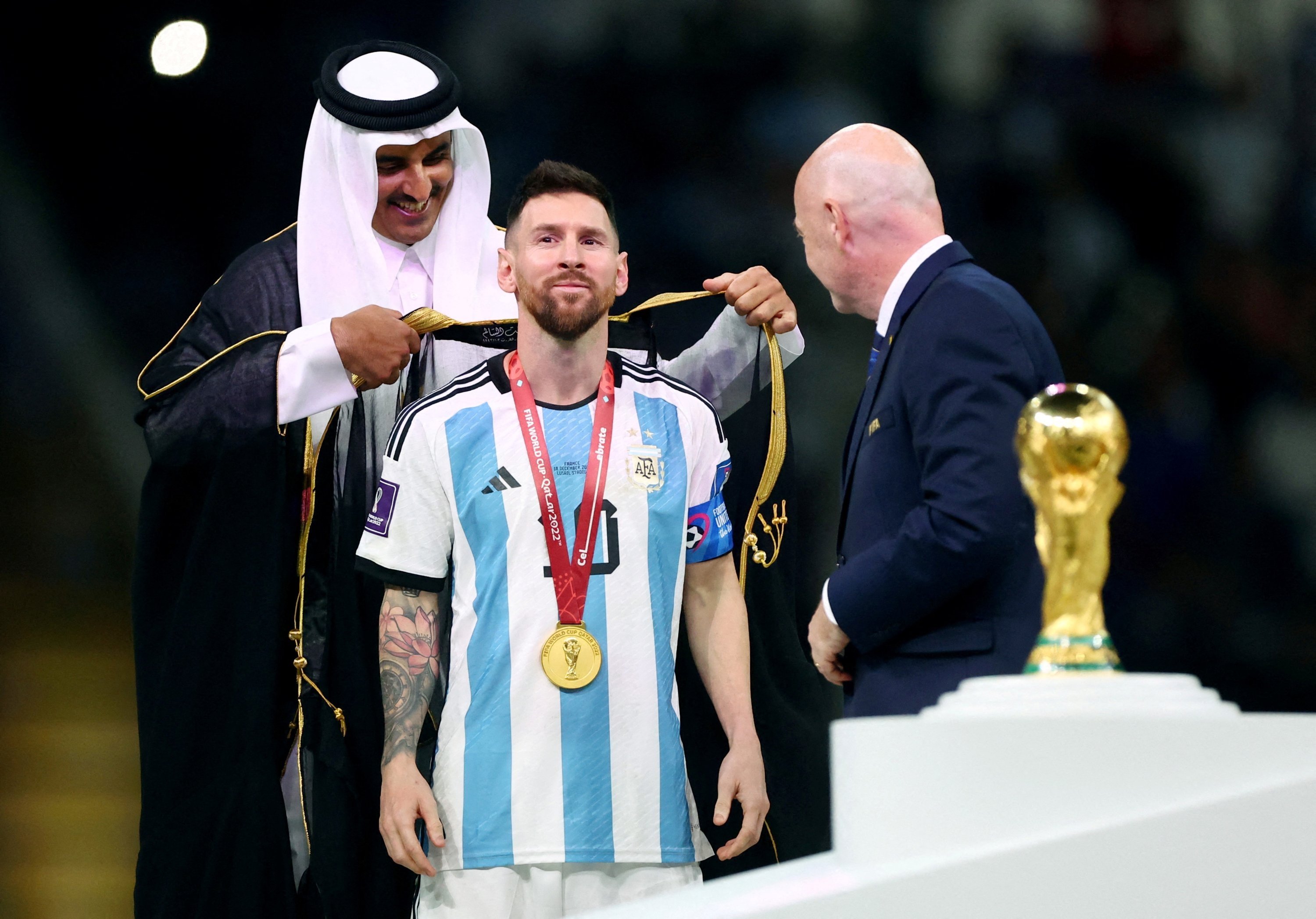 Lionel Messi dari Argentina, Emir Qatar Sheikh Tamim bin Hamad Al Thani dan Presiden FIFA Gianni Infantino saat upacara trofi di Stadion Lusail, Doha, Qatar, 18 Desember 2022. (Foto Reuters)