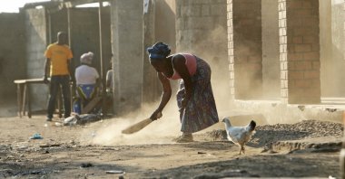 A woman is seen sweeping outside her house in Lusaka, Zambia, Aug. 14, 2021. (AP Photo)