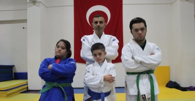 Judoists 15-year-old Gülseren Bürkek (L), 10-year-old Musab Aşan (center front) and 21-year-old Ibrahim Budak (R) pose for a photo with their coach Nihat Özdemir at the Multi-Purpose Sports Hall, Bingöl, Türkiye. (IHA Photo)
