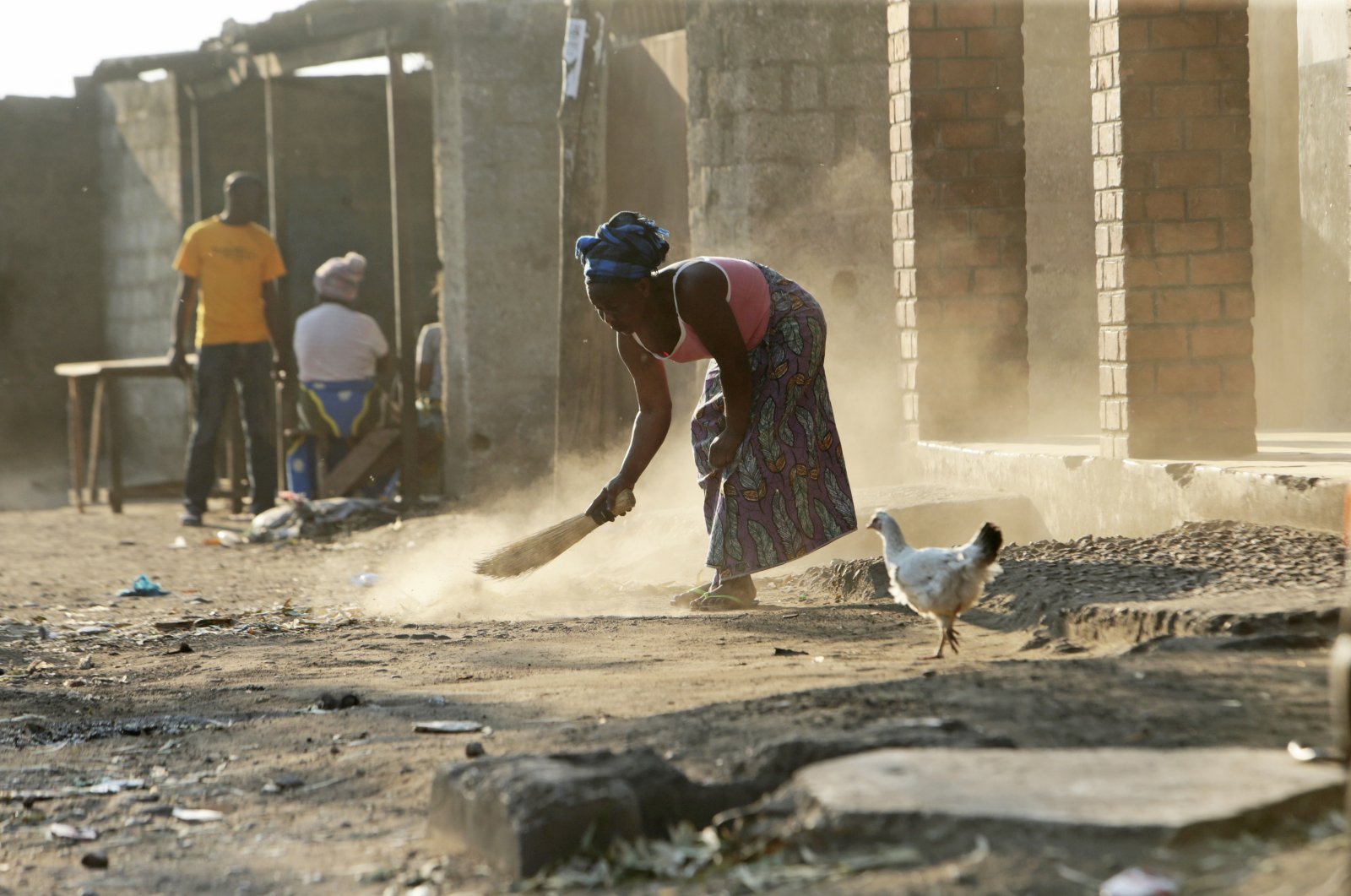 A woman is seen sweeping outside her house in Lusaka, Zambia, Aug. 14, 2021. (AP Photo)