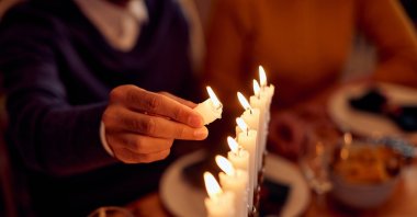 A family member lights a menorah during a dinner on Hanukkah. (Shutterstock Photo)