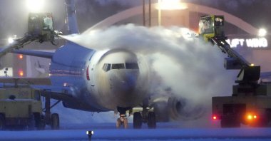 An American Airlines plane is de-iced as high winds whip around 7.5 inches of new snow at Minneapolis-St. Paul International Airport, U.S., Dec. 22, 2022. (AP Photo)