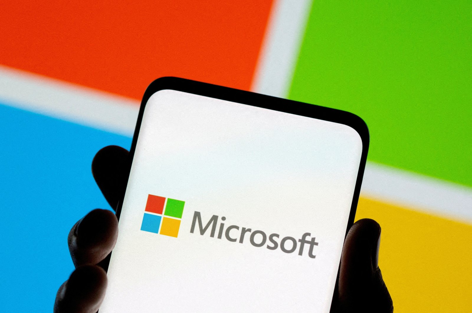 A smartphone is seen in front of the Microsoft logo in this illustration from July 26, 2021. (Reuters Photo)