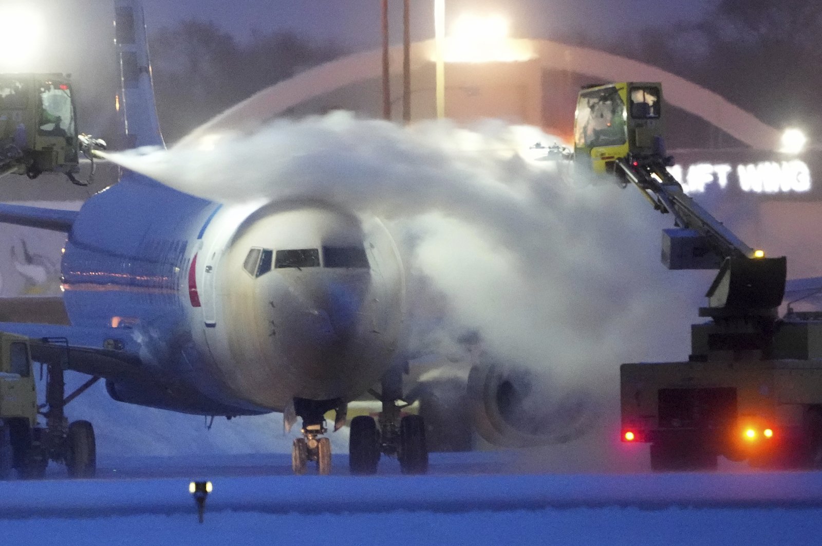 An American Airlines plane is de-iced as high winds whip around 7.5 inches of new snow at Minneapolis-St. Paul International Airport, U.S., Dec. 22, 2022. (AP Photo)