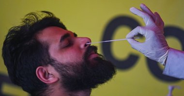A health worker collects a swab sample from a passenger arriving on an international flight during a COVID-19 screening at Anna International Airport in Chennai, India, Dec. 22, 2022. (AFP Photo)
