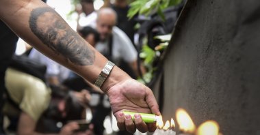 A person with a Pele tattoo lights a candle as fans hold a vigil in support of football legend Pele, who remains hospitalized due to a respiratory infection amid ongoing colon cancer treatments at Albert Einstein Israeli Hospital, Sao Paulo, Brazil, Dec. 4, 2022. (Getty Images Photo)
