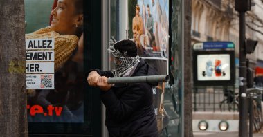 A protestor swings a pipe at a billboard during violent clashes with the police that broke out after a shooting at a Kurdish cultural center in Paris, France, Dec. 24, 2022. (AA Photo)
