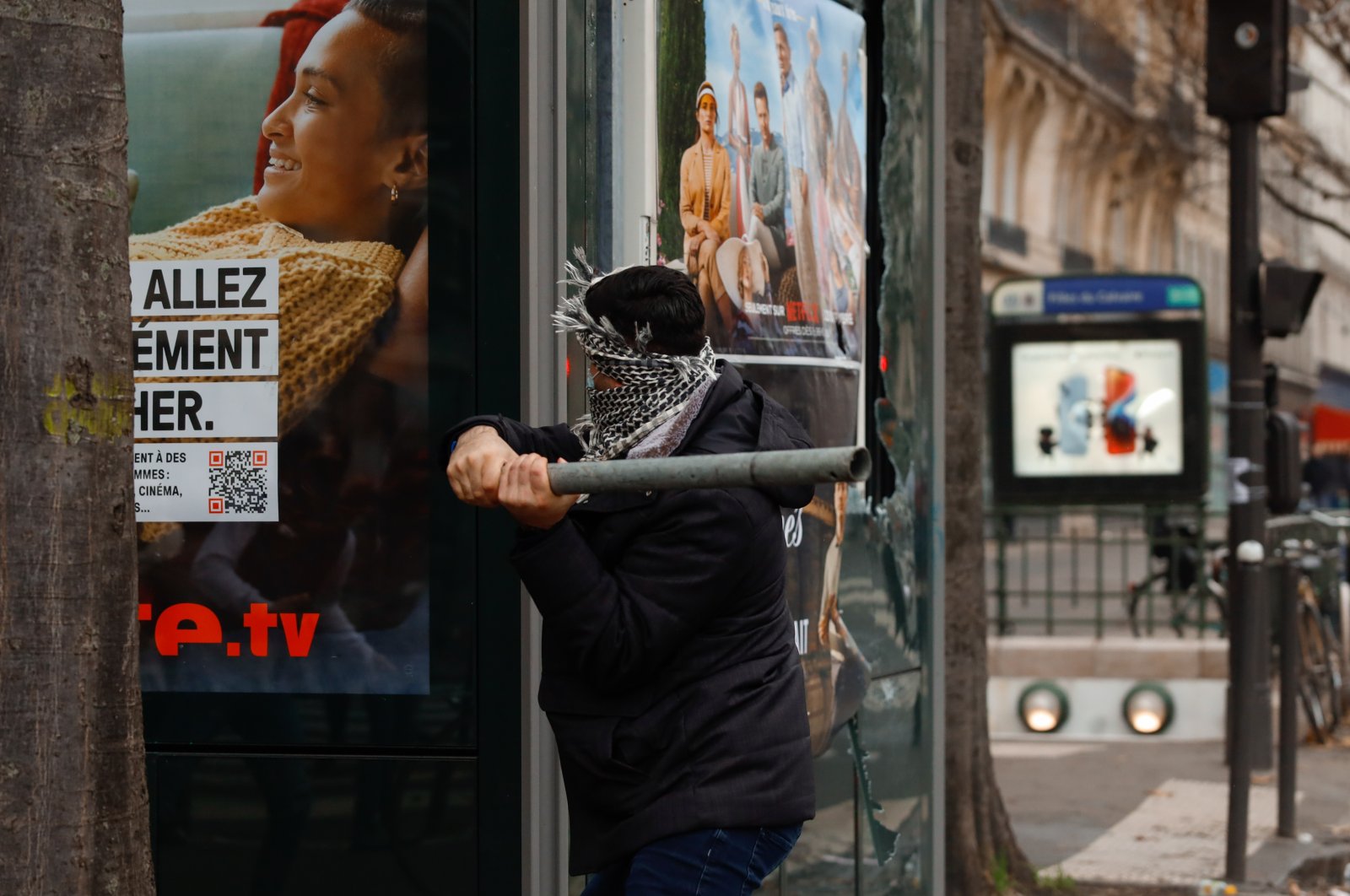 A protestor swings a pipe at a billboard during violent clashes with the police that broke out after a shooting at a Kurdish cultural center in Paris, France, Dec. 24, 2022. (AA Photo)