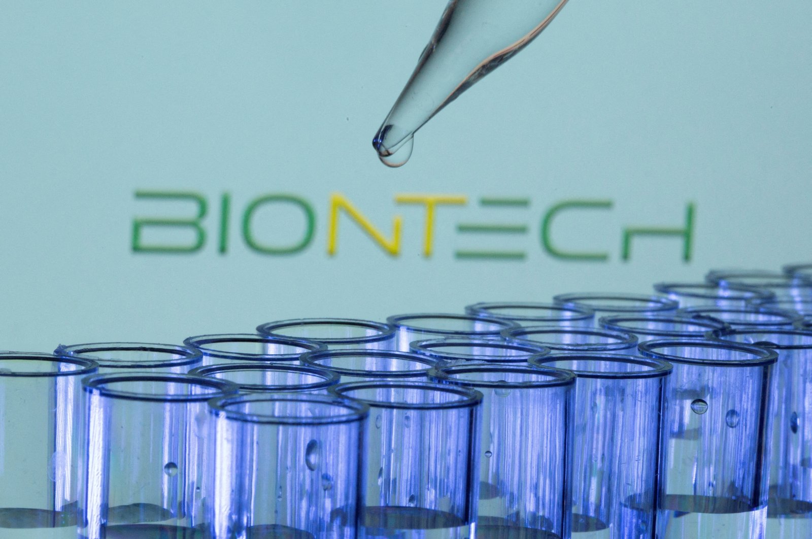 Test tubes are seen in front of a BioNTech logo, May 21, 2021. (Reuters Photo)