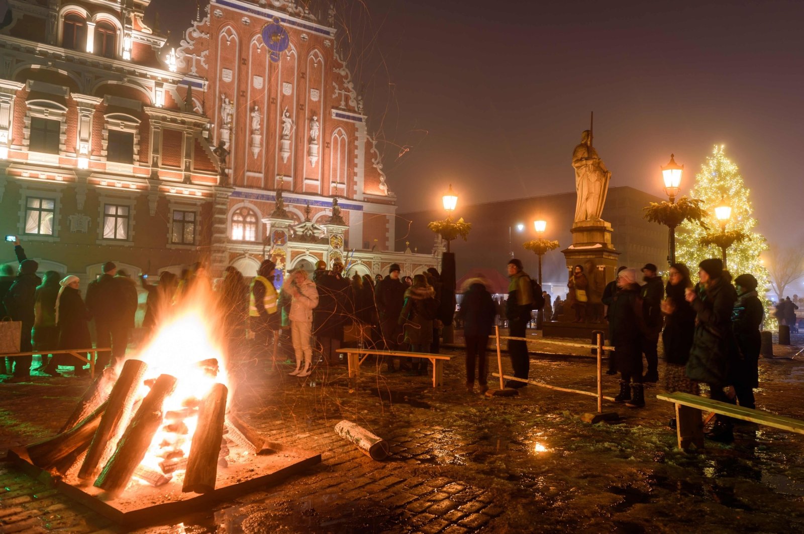 People stand around a fire during the Winter Solstice celebration at the Town Hall Square, in Riga, Latvia, Dec. 21, 2022. (AFP Photo)