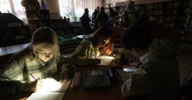 Amid the Russian invasion of Ukraine, children use flashlights as they attend a meeting of their literature club in a public library during a power outage in Irpin, northwest of Kyiv, Dec. 23, 2022. ( AFP Photo)
