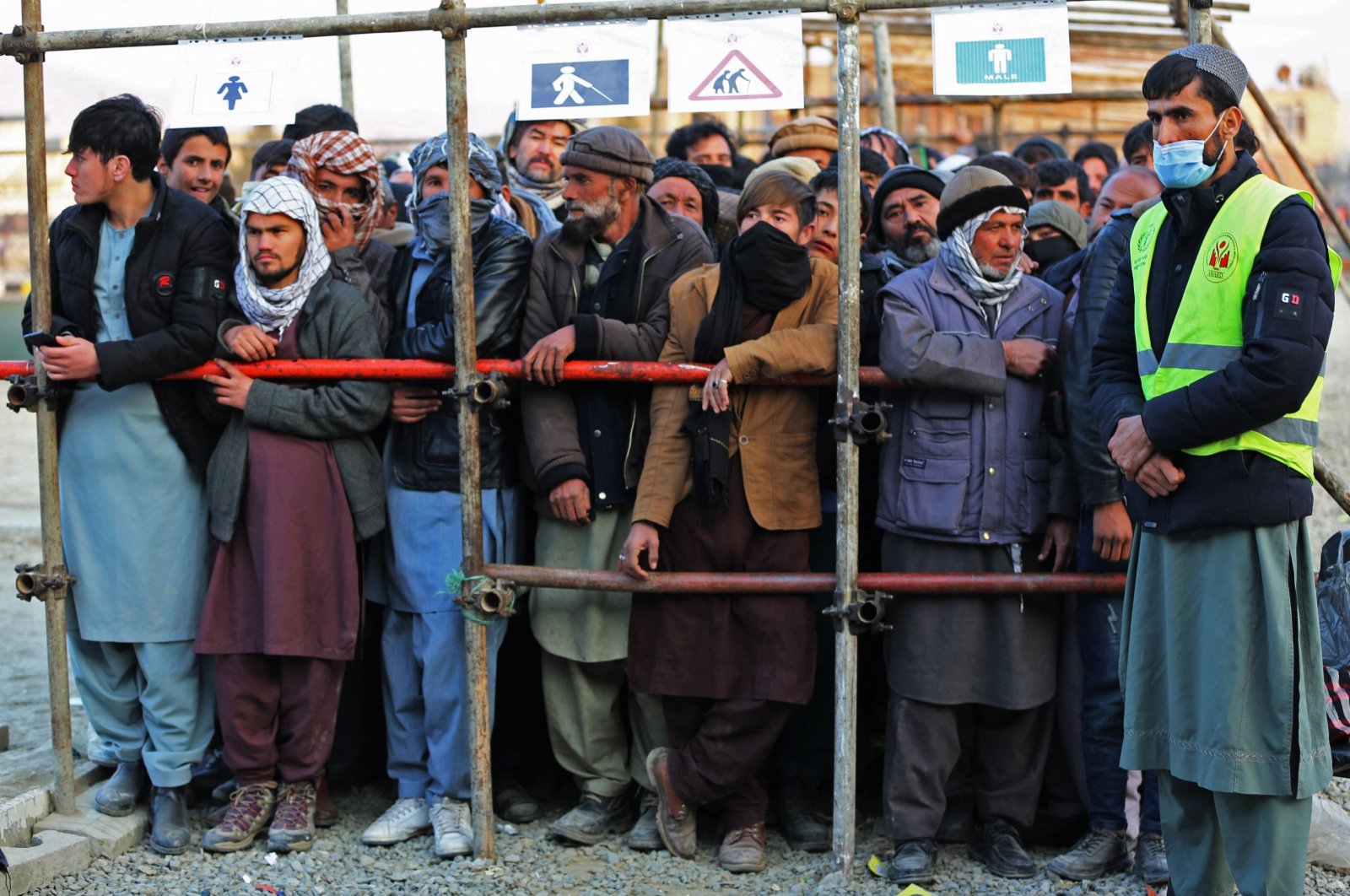 Afghan men stand in queues to receive food aid from an NGO in Kabul, Afghanistan, Dec. 25, 2022. (AFP Photo)