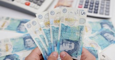A woman holds British Pound banknotes in this illustration taken May 30, 2022. (Reuters Photo)