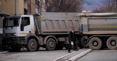 A pedestrian walks past a new road barricade set up in the divided town of Mitrovica on Dec. 28, 2022. (AFP Photo)