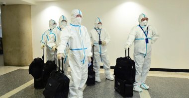 In this file photo taken on Dec. 3, 2021, the flight crew from Air China arrives in hazmat suits at the international terminal at Los Angeles International Airport. (AFP File Photo)