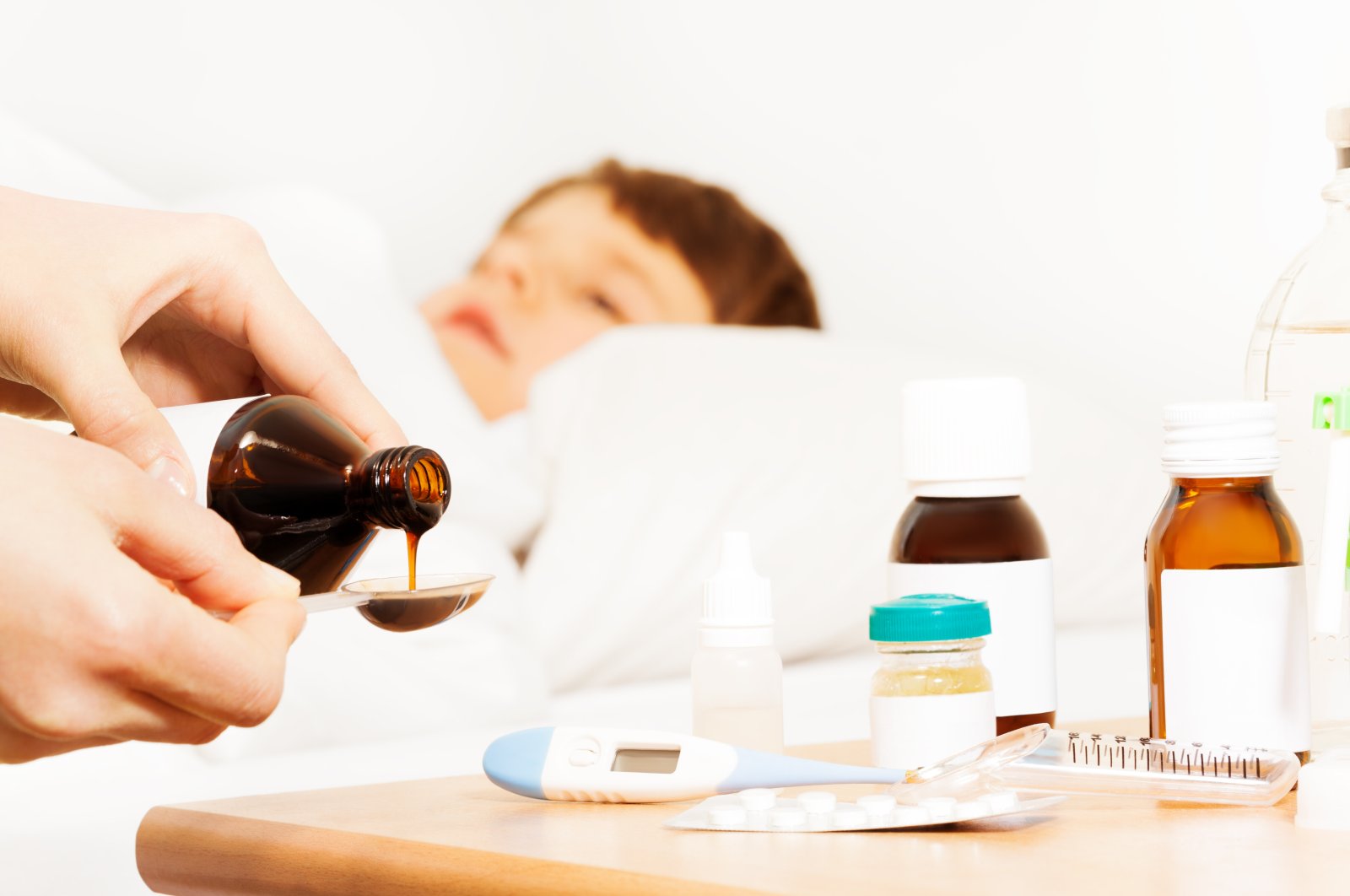 Woman pouring antipyretic syrup for a child in this undated file photo. (Shutterstock File Photo)