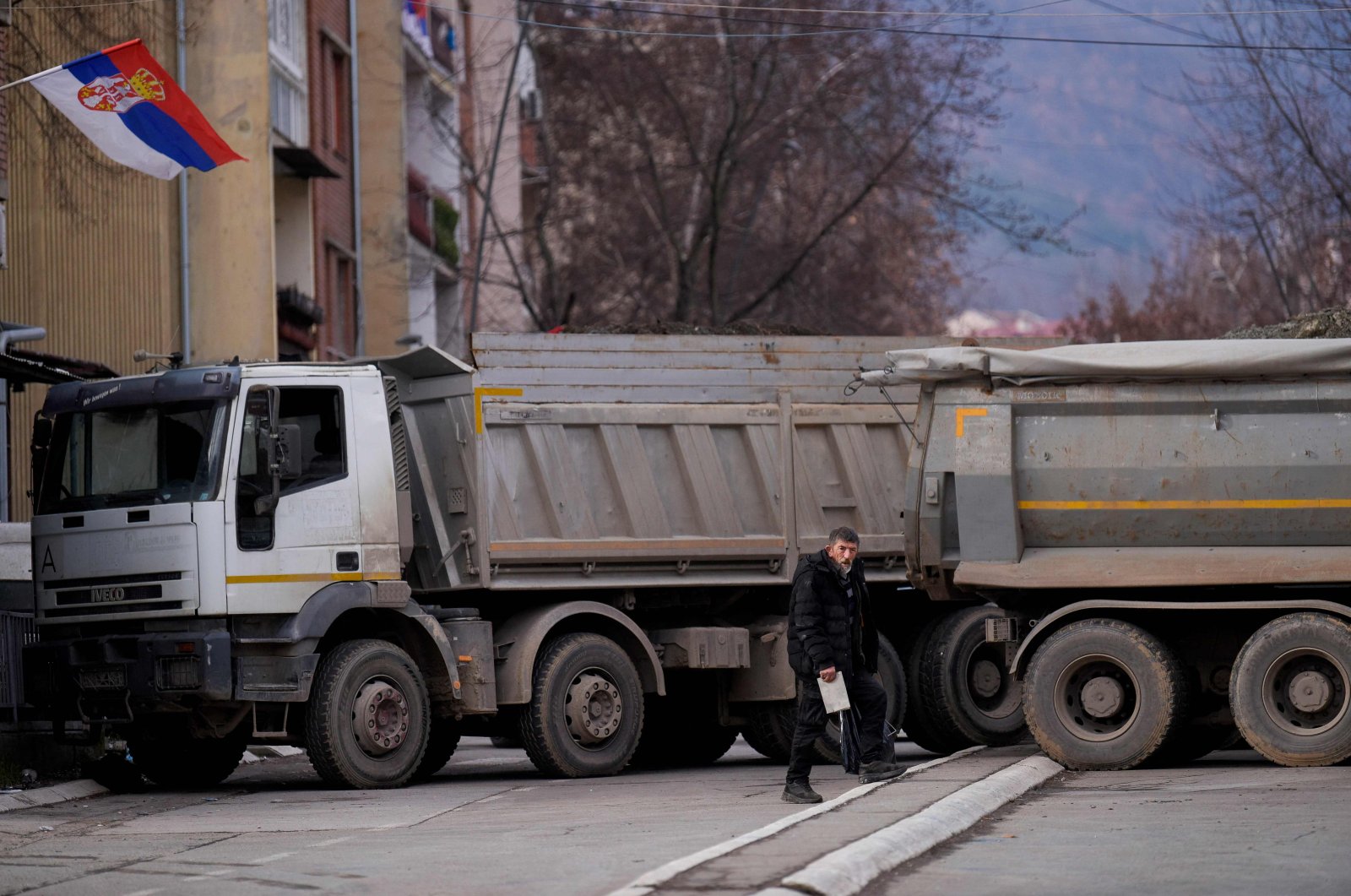 A pedestrian walks past a new road barricade set up in the divided town of Mitrovica on Dec. 28, 2022. (AFP Photo)