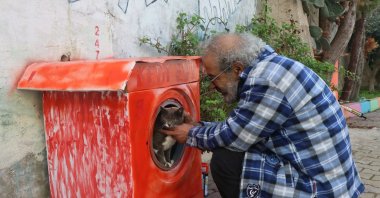 Ahmet Karakayan pets a cat inside his "washing machine" home, in Izmir, western Türkiye, Dec. 28, 2022. (AA Photo)