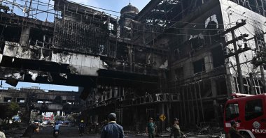 People stand next to a destroyed part of the Grand Diamond City hotel-casino, Poipet, Cambodia, Dec. 29, 2022. (AFP Photo)