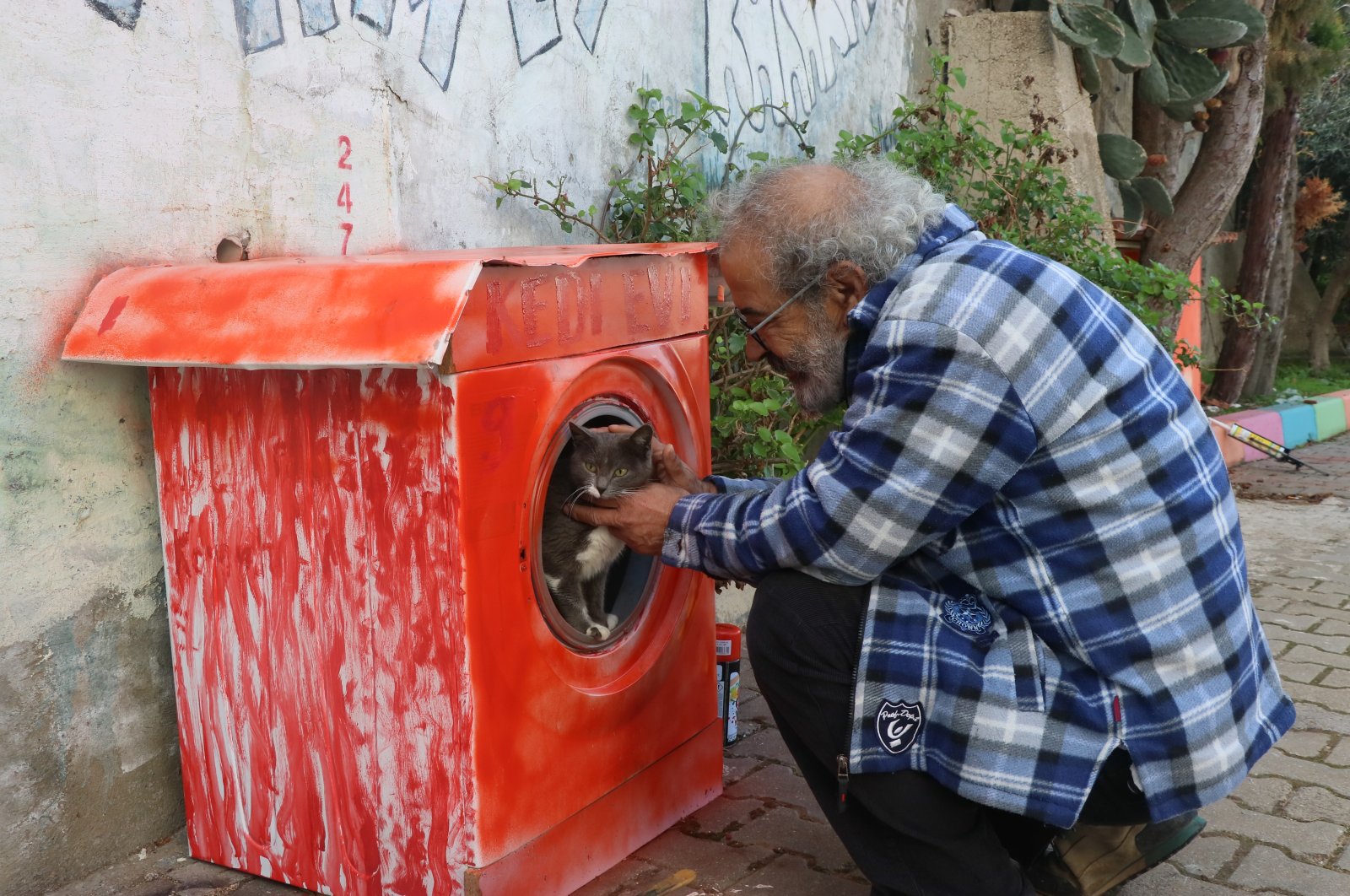 Ahmet Karakayan pets a cat inside his &quot;washing machine&quot; home, in Izmir, western Türkiye, Dec. 28, 2022. (AA Photo)