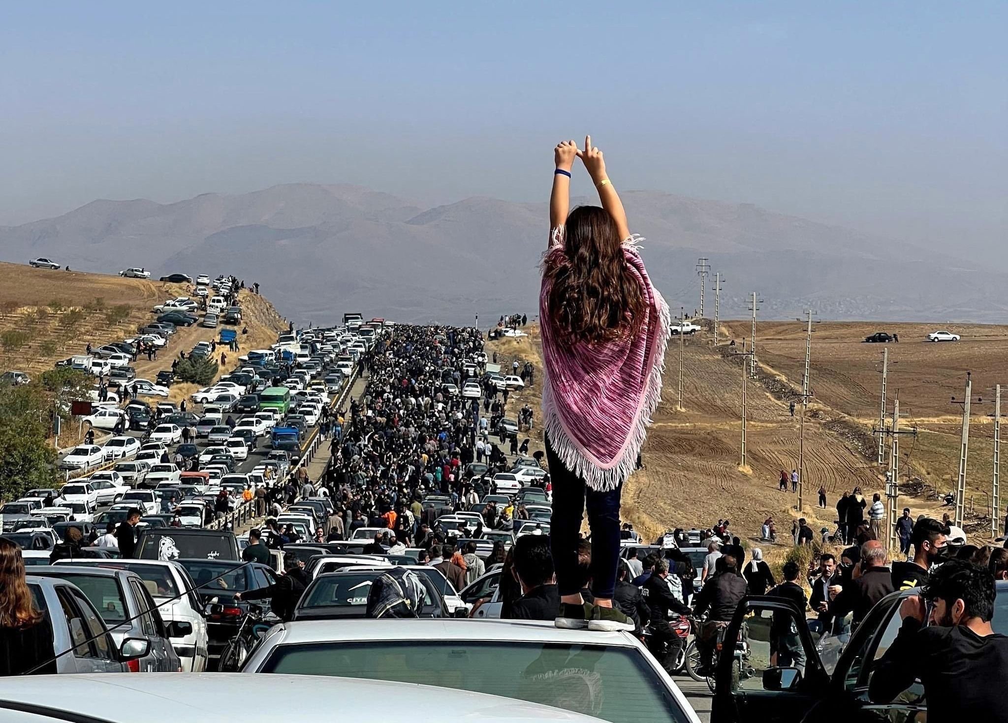Seorang wanita berdiri di atas sebuah kendaraan saat ribuan orang berjalan menuju makam Mahsa Amini, Saqez, Iran, 26 Oktober 2022. (Foto AFP)