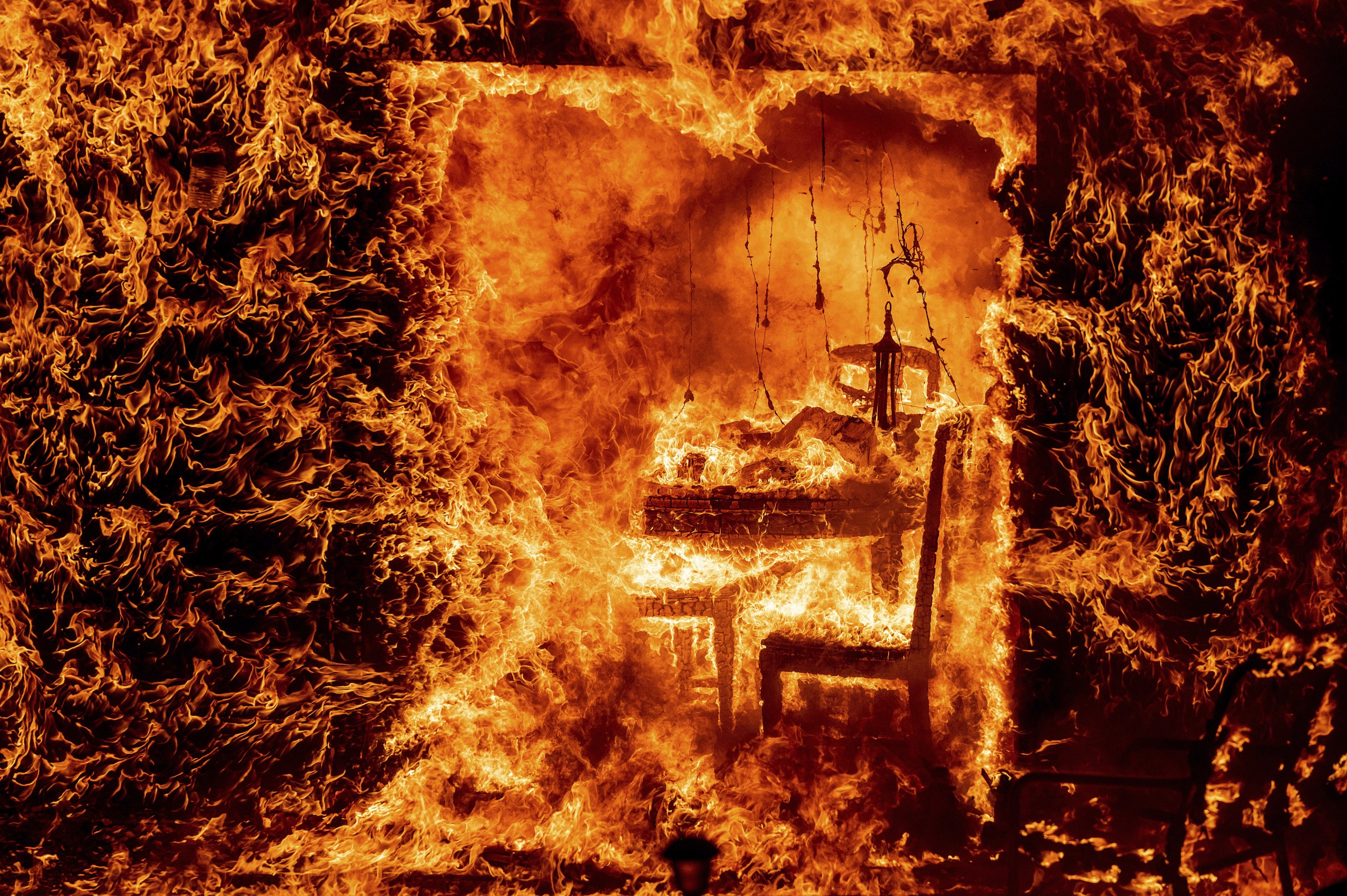 Api melahap kursi di dalam rumah yang terbakar saat Api Oak membakar di Mariposa County, California, AS, pada 23 Juli 2022. (Foto AP)