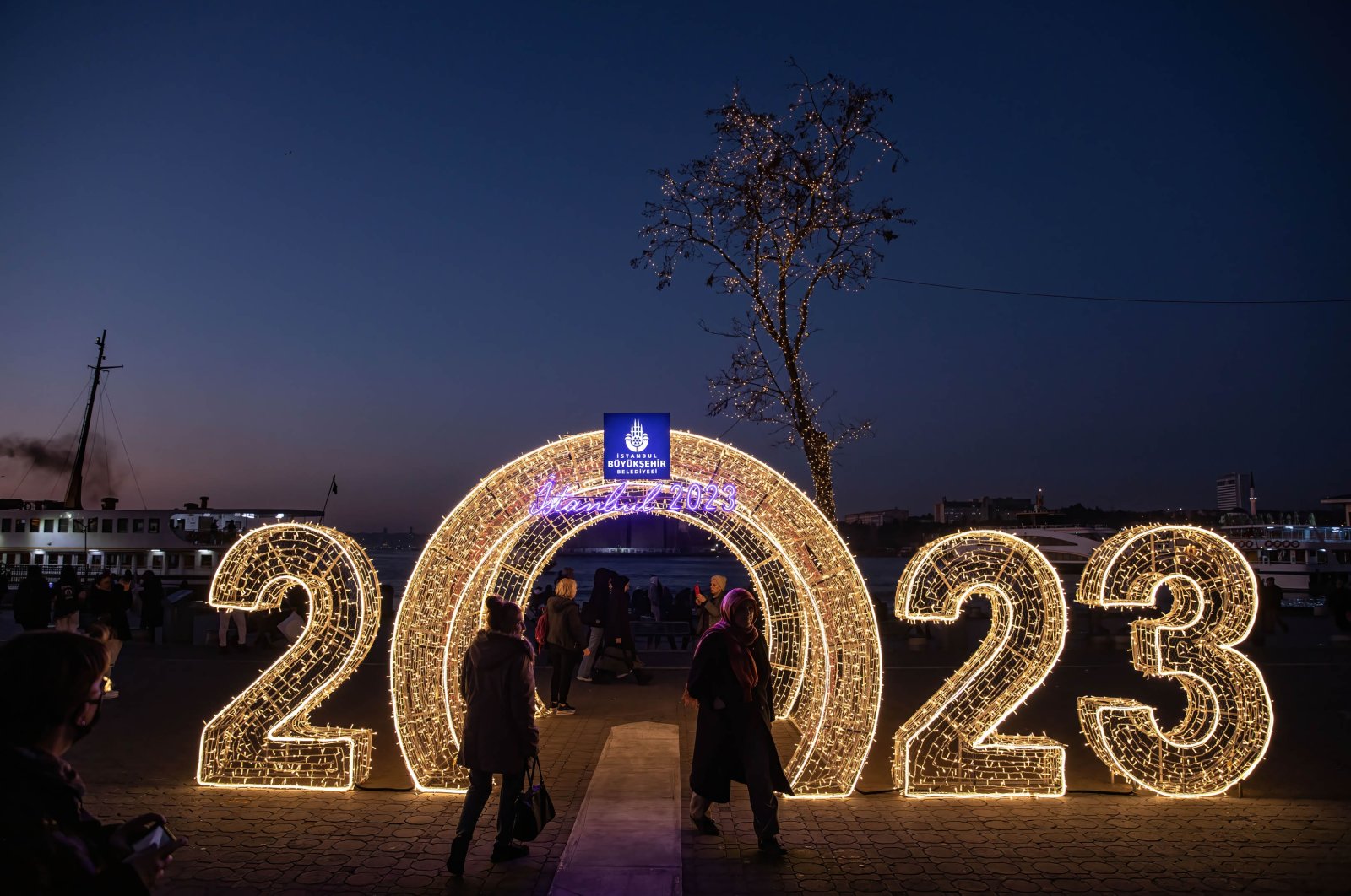 People take photos with their mobile phones in front of the 2023 themed New Year&#039;s lighting during sunset at the Kadıköy pier in Istanbul, Türkiye, Dec. 22, 2022. (Getty Images Photo)