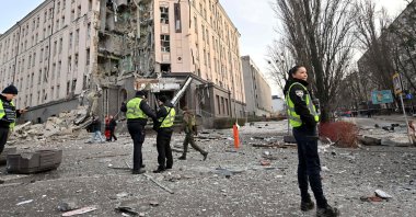 Rescuers and policemen work at the bottom of a hotel, which has been partially destroyed by a Russian strike in the center of the Ukrainian capital, Kyiv on Dec. 31, 2022. (AFP Photo)