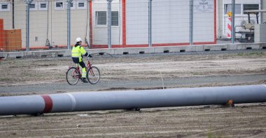 A worker rides a bike next to a pipeline at the landside construction site of the Uniper Liquefied Natural Gas (LNG) terminal at the Jade Bight in Wilhelmshaven on the North Sea coast, northwestern Germany, Sept. 29, 2022. (AFP Photo)