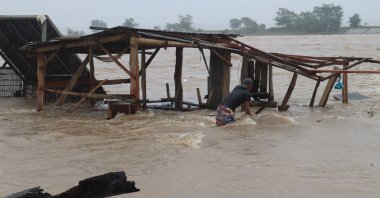 A vendor tries to salvage materials from a submerged stall after a river overflowed due to heavy rains brought by monsoons in the north of Manila, Philippines, Jan. 1, 2023. (AFP Photo)