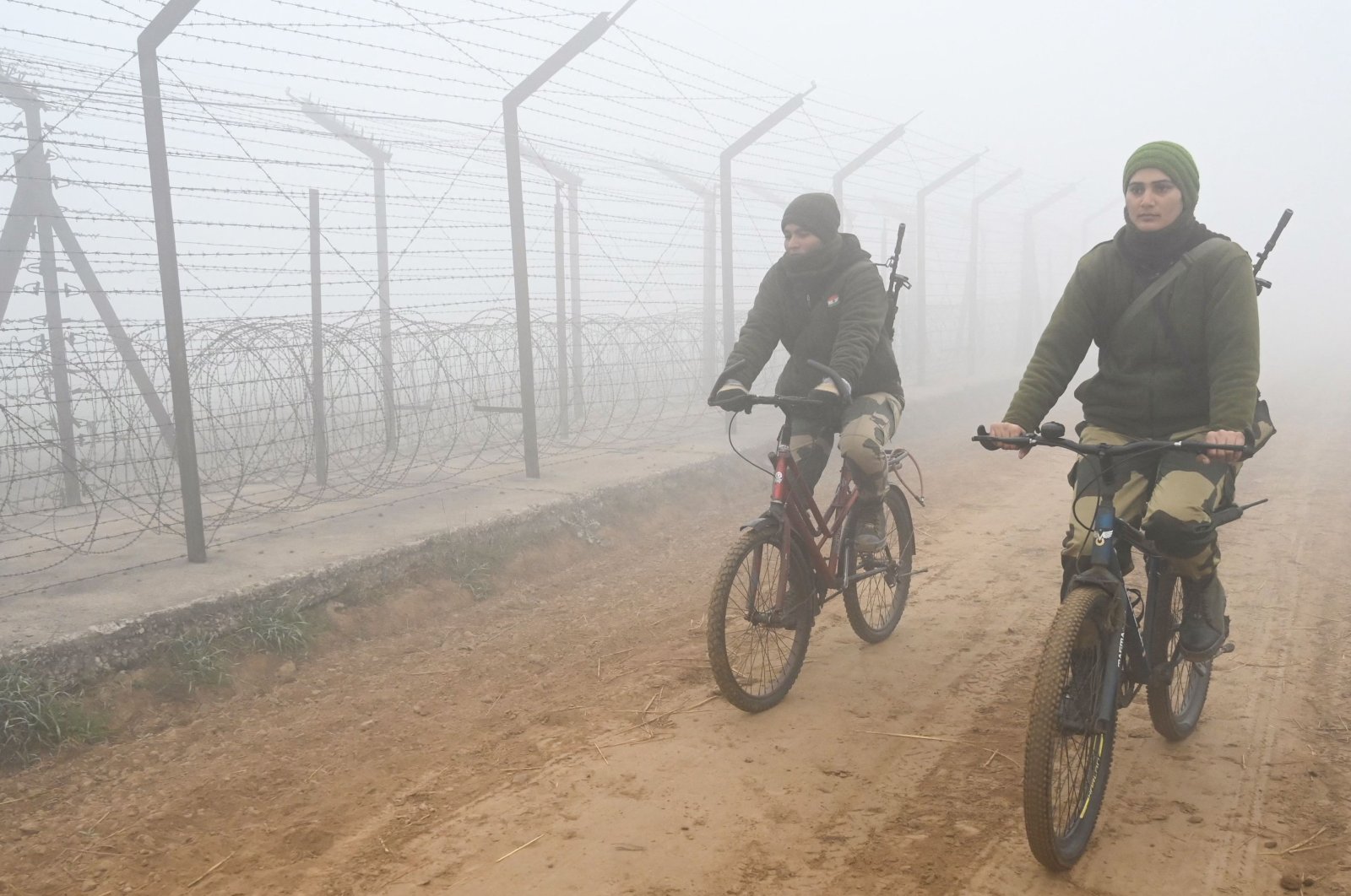 Border Security Force (BSF) personnel patrol along the border fence on bicycles during a cold foggy morning at the India-Pakistan Wagah border near Amritsar, India, Dec. 21, 2022. (AFP Photo)