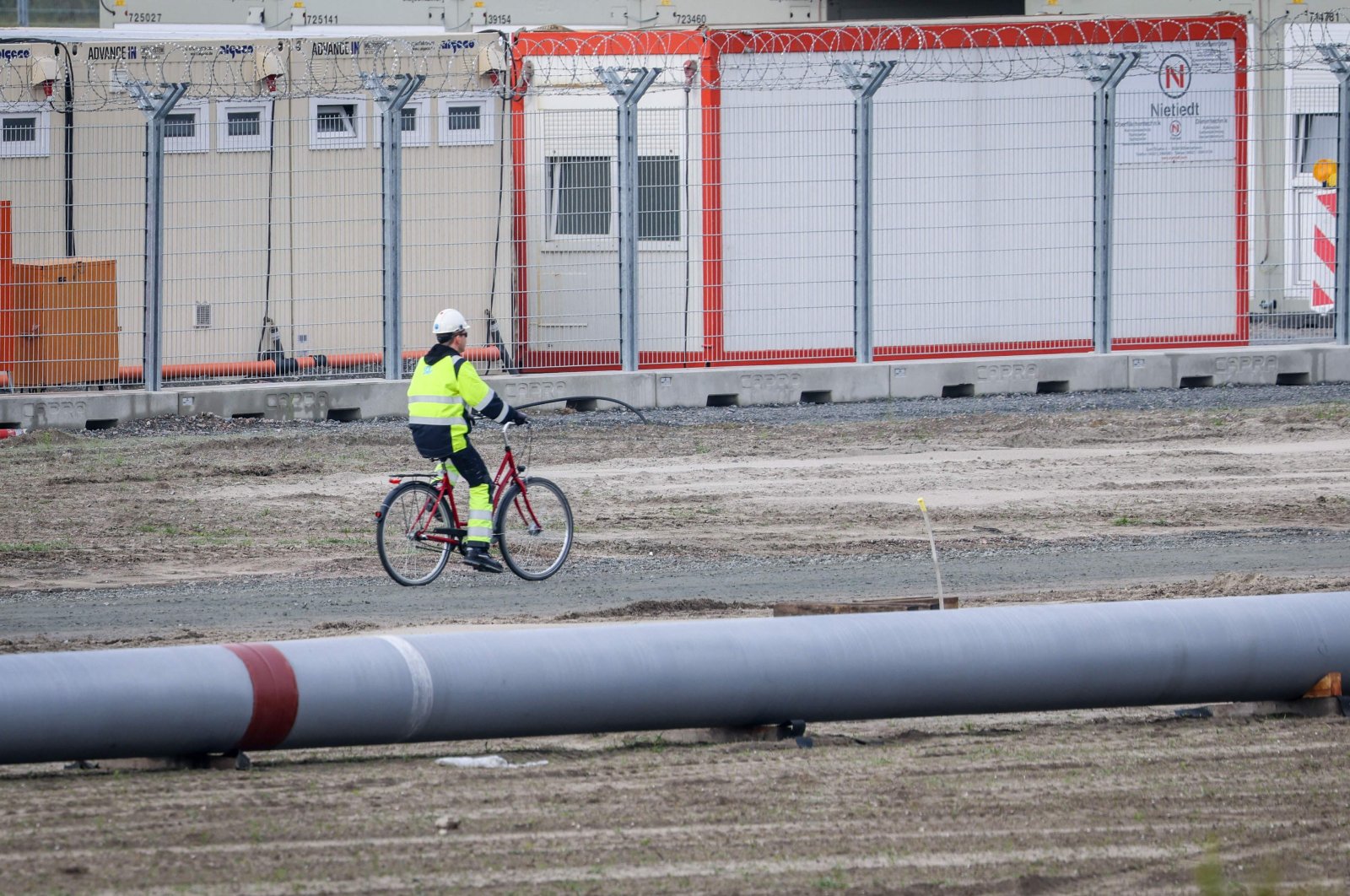 A worker rides a bike next to a pipeline at the landside construction site of the Uniper Liquefied Natural Gas (LNG) terminal at the Jade Bight in Wilhelmshaven on the North Sea coast, northwestern Germany, Sept. 29, 2022. (AFP Photo)