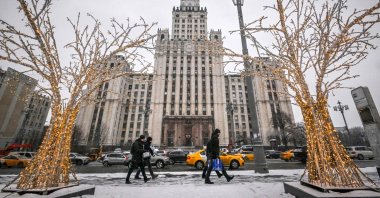 Pedestrians walk past Christmas and New Year decorations in front of the Red Gate Building Stalin-era skyscraper in Moscow, Russia, Dec. 28, 2022. (AFP Photo)