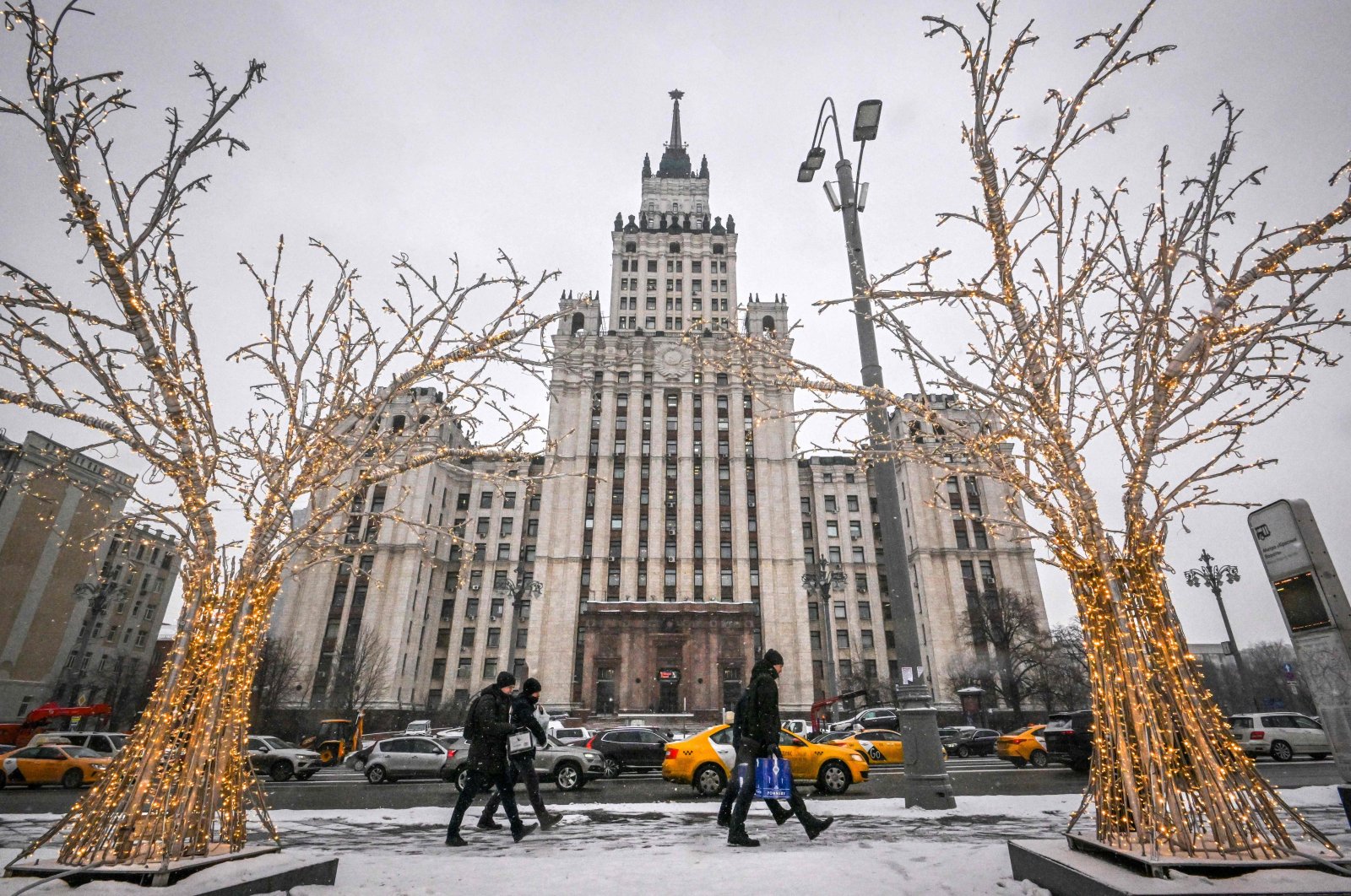 Pedestrians walk past Christmas and New Year decorations in front of the Red Gate Building Stalin-era skyscraper in Moscow, Russia, Dec. 28, 2022. (AFP Photo)