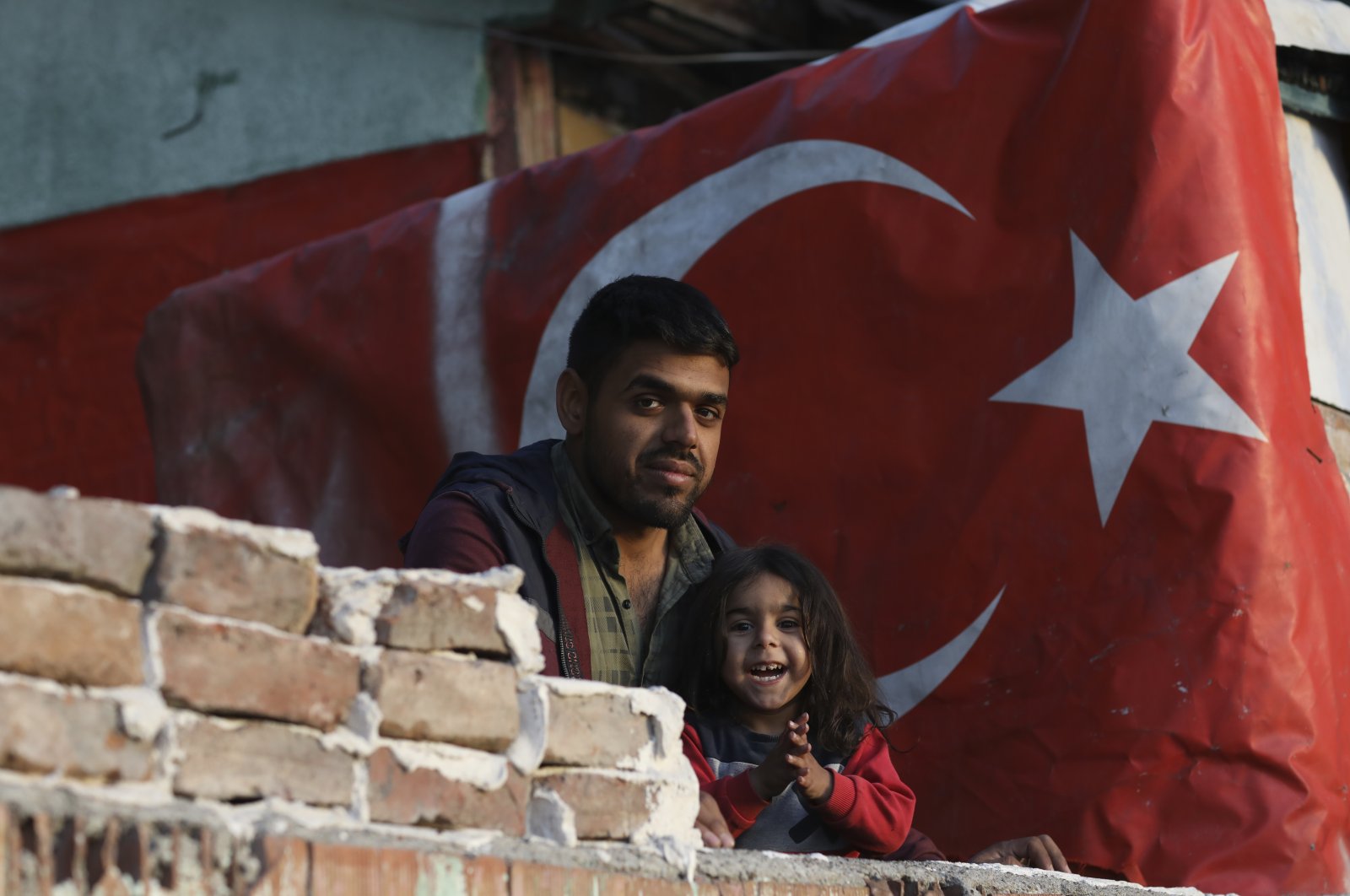 A Syrian migrant man and daughter stand in front of their shelter in Ulus district, the old part of the capital Ankara, Türkiye, Oct. 23, 2022. (AP Photo)