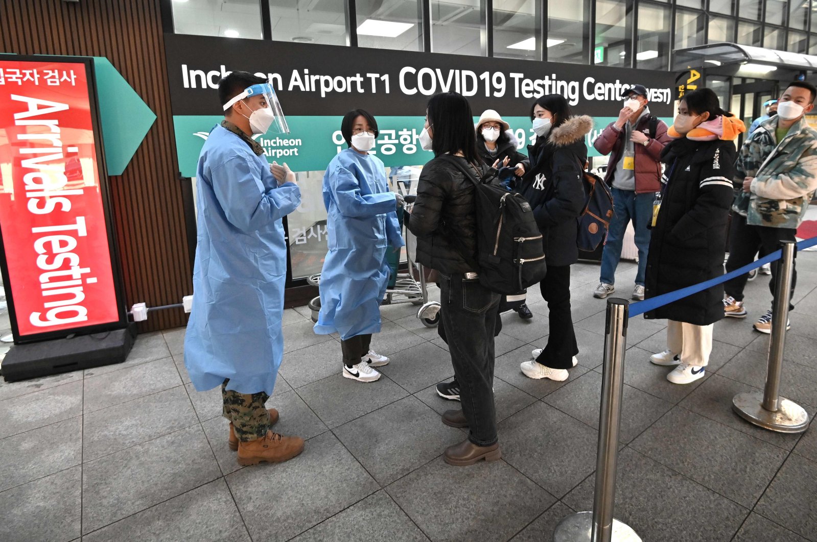 Health workers guide travelers arriving from China in front of a COVID-19 testing center at Incheon International Airport, Seoul, South Korea, Jan. 3, 2023. (AFP Photo)