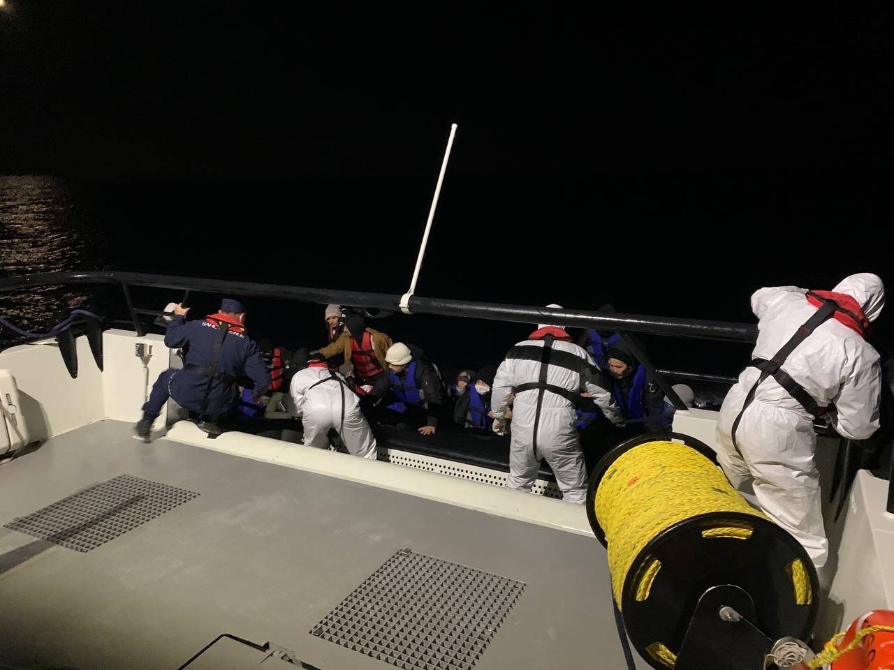 The Turkish coast guard help some 30 irregular migrants out of their raft into a boat after they were pushed back by Greek authorities off the coast of Türkiye&#039;s western Çanakkale province, Jan. 3, 2023. (AA Photo)