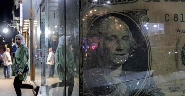 A woman walks out of a currency exchange shop displaying a giant U.S. dollar banknote in the Zamalek district of Cairo, Egypt, Aug. 24, 2022. (AFP Photo)