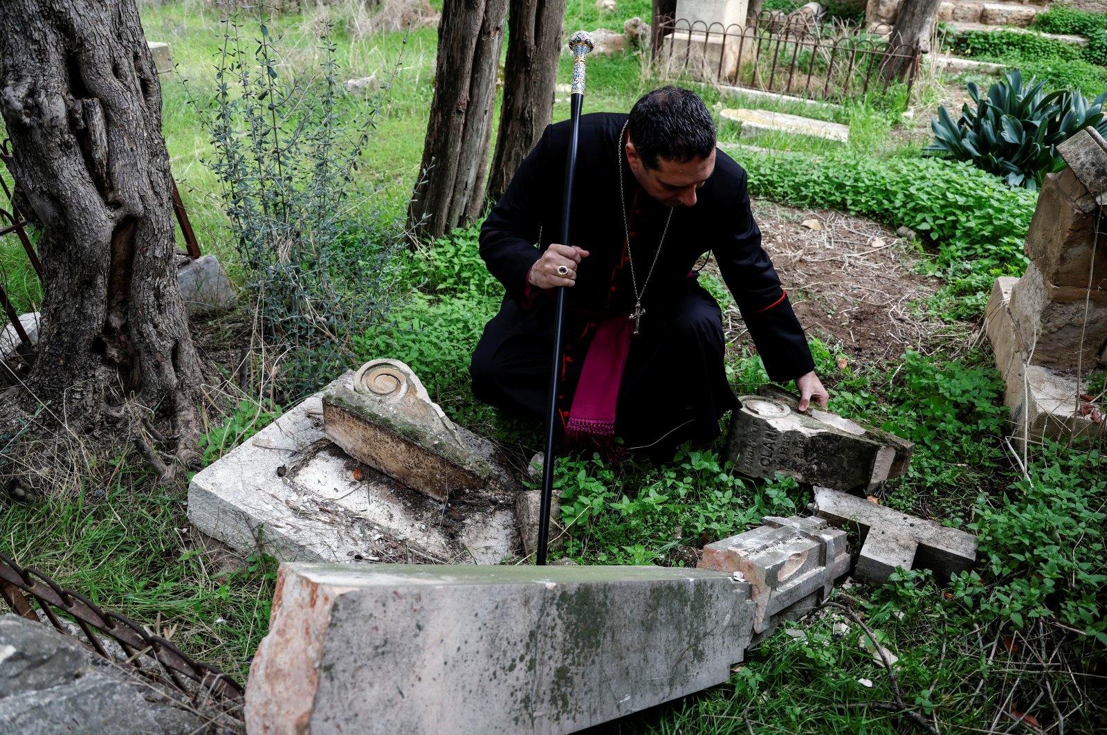 Archbishop Hosam Naoum inspects a vandalized tombstone at the Protestant Mount Zion Cemetery in Jerusalem Jan. 4, 2023. (Reuters File Photo)