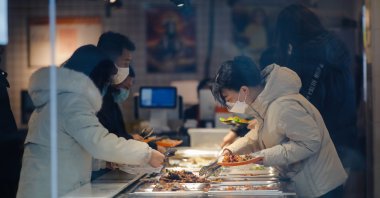 People wearing face masks pick food in a cafeteria in Beijing, China, Dec. 8, 2022. (EPA Photo)