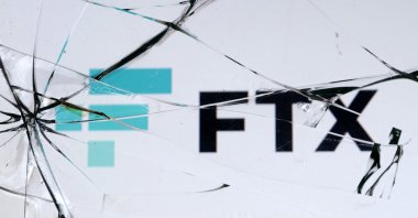 An FTX logo is seen through broken glass in this illustration taken, Dec. 13, 2022. (Reuters Photo)
