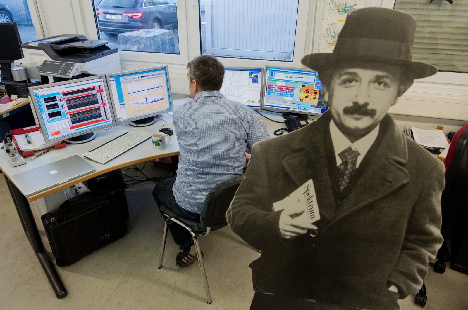 An employee sits in front of screens in the gravitational waves detector next to a cardboard display of Albert Einstein, Lower Saxony, Sarstedt, Germany, Jan. 22, 2019. (Getty Images)