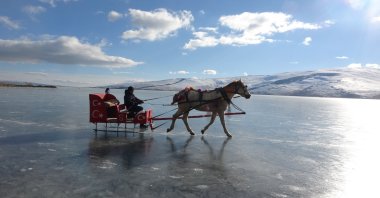 People ride in a troika on the frozen surface of Lake Çıldır in the Çıldır district of Ardahan province, eastern Türkiye, Jan. 6, 2023. (IHA Photo)