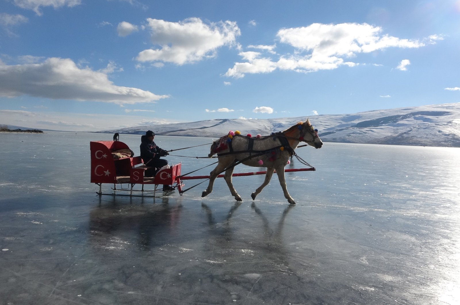People ride in a troika on the frozen surface of Lake Çıldır in the Çıldır district of Ardahan province, eastern Türkiye, Jan. 6, 2023. (IHA Photo)